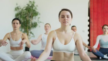 Yoga farkındalığı meditasyonu. Yoga sağlık farkındalığı meditasyonu için stüdyoda egzersiz yapan bir grup sporcu. Nilüfer çiçeğinde oturup yoga yapan erkek kadınlar meditasyon yapıyor.