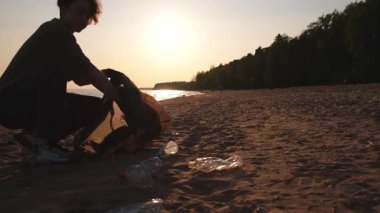 Dünya günü. Gönüllü eylemciler sahil bölgesindeki çöpleri topluyor. Kadınlar ve erkekler okyanus kıyısındaki çöp torbasına plastik çöp koyar. Çevre koruma kıyı bölgesi temizliği
