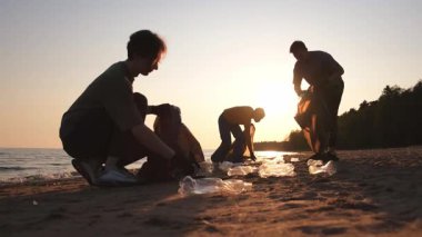 Dünya günü. Gönüllü eylemciler sahil bölgesindeki çöpleri topluyor. Kadınlar ve erkekler okyanus kıyısındaki çöp torbasına plastik çöp koyar. Çevre koruma kıyı bölgesi temizliği