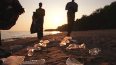 Dünya günü. Gönüllü eylemciler sahil bölgesindeki çöpleri topluyor. Kadınlar ve erkekler okyanus kıyısındaki çöp torbasına plastik çöp koyar. Çevre koruma kıyı bölgesi temizliği
