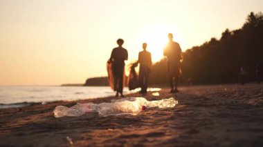 Dünya günü. Gönüllü eylemciler sahil bölgesindeki çöpleri topluyor. Kadınlar ve erkekler okyanus kıyısındaki çöp torbasına plastik çöp koyar. Çevre koruma kıyı bölgesi temizliği