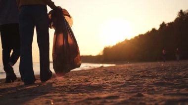 Dünya günü. Gönüllü eylemciler, sahil bölgesindeki çöpleri topluyor. Okyanus kıyısında çöp torbası içinde kadın erkekler. Çevre koruma kıyı bölgesi temizliği