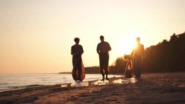 Dünya günü. Gönüllü eylemciler, sahil bölgesindeki çöpleri topluyor. Okyanus kıyısında çöp torbası içinde kadın erkekler. Çevre koruma kıyı bölgesi temizliği