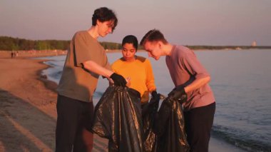 Dünya günü. Gönüllü eylemciler, sahil bölgesindeki çöpleri topluyor. Okyanus kıyısında çöp torbası içinde kadın erkekler. Çevre koruma kıyı bölgesi temizliği