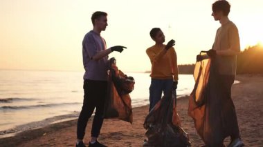 Dünya günü. Gönüllü eylemciler, sahil bölgesindeki çöpleri topluyor. Okyanus kıyısında çöp torbası içinde kadın erkekler. Çevre koruma kıyı bölgesi temizliği