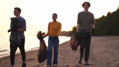 Dünya günü. Gönüllü eylemciler, sahil bölgesindeki çöpleri topluyor. Okyanus kıyısında çöp torbası içinde kadın erkekler. Çevre koruma kıyı bölgesi temizliği