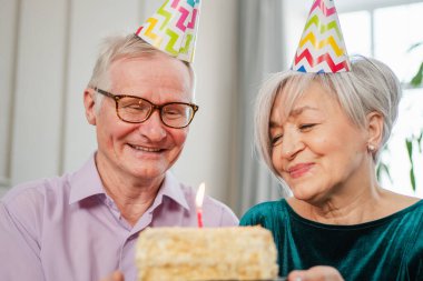 Bir dilek tut. Parti şapkalı son sınıf aile çifti evde birlikte doğum günü kutluyor. Yaşlı kadın doğum günü pastasında yanan mumları üflüyor. Yaşlı adam karısına mutlu yıllar diliyor.