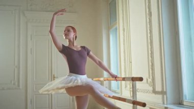 Tutu etekli genç balerin dans sınıfında bale pozisyonlarında dans ediyor. Dans stüdyosundaki genç klasik dansçı kadın. Bale sınıfı eğitim konsepti