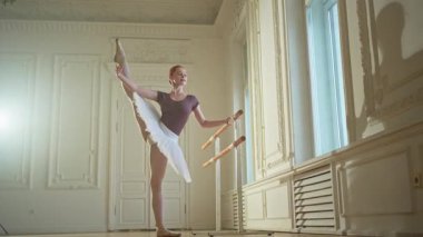 Tutu etekli genç balerin dans sınıfında bale pozisyonlarında dans ediyor. Dans stüdyosundaki genç klasik dansçı kadın. Bale sınıfı eğitim konsepti