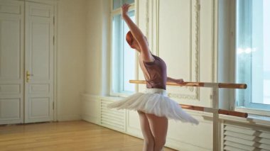 Tutu etekli genç balerin dans sınıfında bale pozisyonlarında dans ediyor. Dans stüdyosundaki genç klasik dansçı kadın. Bale sınıfı eğitim konsepti