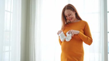 Hamilelik anneliği insanların gelecek beklentisi. Koca göbekli hamile bir kadın kucağında bebek poposu ile evde gülümsüyor. Genç anne hamileliğin tadını çıkarıyor. Annelik şefkati ebeveynlik yeni bir hayat