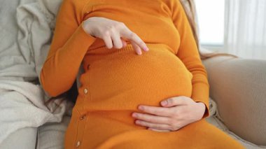 Hamilelik anneliği insanların gelecek beklentisi. Hamile kadın elleri pencerenin yanındaki koca göbeğe dokunuyor. Karnına sarılan ve hamileliğin tadını çıkaran bir kız. Annelik şefkati ebeveynlik yeni yaşam konsepti