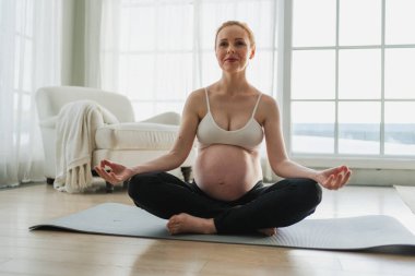 Hamilelik öncesi nefes alma. Koca göbekli hamile bir kadın nilüfer çiçeğinin üstünde yoga pozu veriyor. Hamile kız yoga farkındalığı meditasyonu yapıyor. Hamilelik sırasındaki rahatlama.