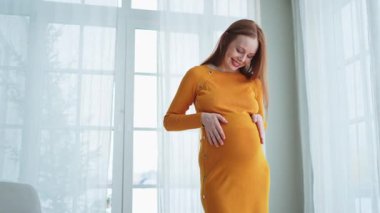 Hamilelik anneliği insanların gelecek beklentisi. Evinin penceresinin yanında koca göbekli hamile bir kadın var. Karnına sarılan ve hamileliğin tadını çıkaran bir kız. Annelik şefkati ebeveynlik yeni yaşam konsepti