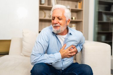 Kalp krizi, kalp krizi. Memnuniyetsiz orta yaşlı adam göğüs ağrısı çekiyor kalp krizi geçiriyor evde sağlık sorunları var. Yaşlı büyükbaba göğsüne dokunuyor ve damar tıkanıklığı yaşıyor.
