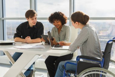 Takım çalışması beyin fırtınası. Çeşitli çok ırklı iş arkadaşları olan kadın engelliler için birlikte çalışıyor. Yaratıcı ofiste oturup iş konuşan bir grup insan. Genç profesyonel takım