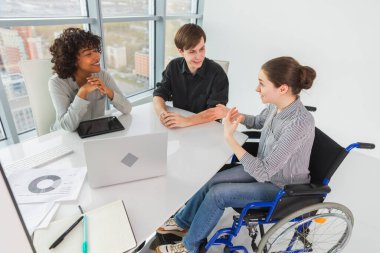 Takım çalışması beyin fırtınası. Çeşitli çok ırklı iş arkadaşları olan kadın engelliler için birlikte çalışıyor. Yaratıcı ofiste oturup iş konuşan bir grup insan. Genç profesyonel takım