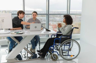 Takım çalışması beyin fırtınası. Çeşitli çok ırklı iş arkadaşları olan kadın engelliler için birlikte çalışıyor. Yaratıcı ofiste oturup iş konuşan bir grup insan. Genç profesyonel takım