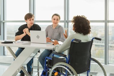 Takım çalışması beyin fırtınası. Çeşitli çok ırklı iş arkadaşları olan kadın engelliler için birlikte çalışıyor. Yaratıcı ofiste oturup iş konuşan bir grup insan. Genç profesyonel takım