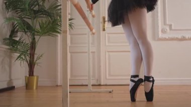 Balerin dans sınıfında bale pozisyonunda dans ediyor, sivri uçlu ayakkabılar giyiyor. Dans stüdyosu sınıfında bale ayakkabısı. Dans stüdyosundaki klasik balerin kadın. Bale okulu konsepti