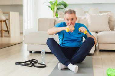 Fitness antrenmanı. Üst düzey boksör dambılları kaldırıyor. Yetişkin, sağlıklı bir adam evde spor yapıyor. Büyükbabanın rehabilitasyonu var. Sağlık hizmetleri sağlıklı yaşam tarzı