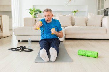Fitness antrenmanı. Üst düzey boksör dambılları kaldırıyor. Yetişkin, sağlıklı bir adam evde spor yapıyor. Büyükbabanın rehabilitasyonu var. Sağlık hizmetleri sağlıklı yaşam tarzı
