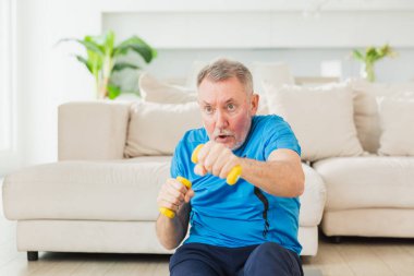 Fitness antrenmanı. Üst düzey boksör dambılları kaldırıyor. Yetişkin, sağlıklı bir adam evde spor yapıyor. Büyükbabanın rehabilitasyonu var. Sağlık hizmetleri sağlıklı yaşam tarzı