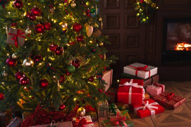 Klasik Noel dekore edilmiş şömineli oturma odası. Kırmızı altın süslemeli Noel ağacı hediye kutuları. Modern klasik iç tasarım dairesi. Evde Noel arifesi