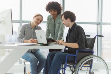 Takım çalışması beyin fırtınası. Çeşitli çok ırklı meslektaşlar birlikte çalışan engelli insanlar için sandalyede oturuyor. Yaratıcı ofiste oturup iş konuşan bir grup insan. Genç profesyonel takım