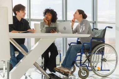 Takım çalışması beyin fırtınası. Çeşitli çok ırklı iş arkadaşları olan kadın engelliler için birlikte çalışıyor. Yaratıcı ofiste oturup iş konuşan bir grup insan. Genç profesyonel takım