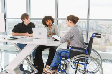 Takım çalışması beyin fırtınası. Çeşitli çok ırklı iş arkadaşları olan kadın engelliler için birlikte çalışıyor. Yaratıcı ofiste oturup iş konuşan bir grup insan. Genç profesyonel takım