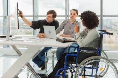 Takım çalışması beyin fırtınası. Çeşitli çok ırklı iş arkadaşları olan kadın engelliler için birlikte çalışıyor. Yaratıcı ofiste oturup iş konuşan bir grup insan. Genç profesyonel takım