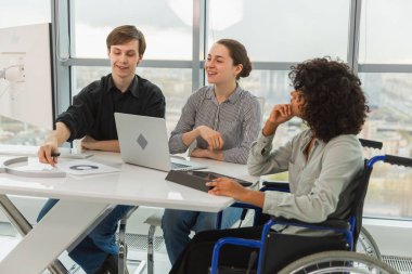 Takım çalışması beyin fırtınası. Çeşitli çok ırklı iş arkadaşları olan kadın engelliler için birlikte çalışıyor. Yaratıcı ofiste oturup iş konuşan bir grup insan. Genç profesyonel takım