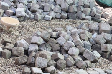 Arazi düzenlemesi ve yenileme çalışmaları için düzensiz gri kaldırım taşları yığını.