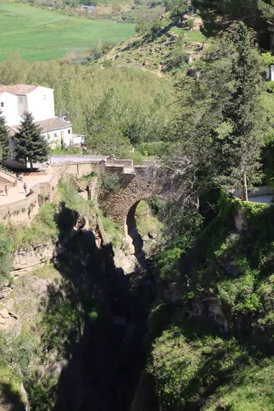 Turistler, tarihi bir şehir olan Ronda 'daki Puente Nuevo köprüsünün yanında yürüyorlar.