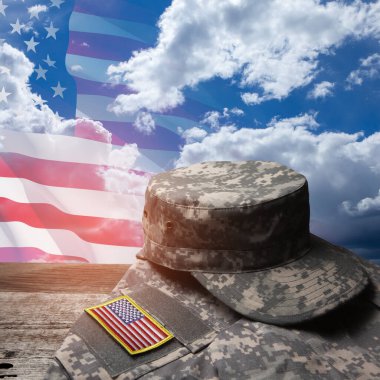 USA military uniform with insignias on old wooden table on blue sky background with USA flag. Memorial Day or Veterans day concept.