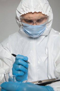 Scientific virologist. Biologist in protective suit and blue gloves takes notes. Viruses concept. Virus University employee.