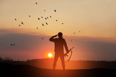 Silhouette of soldier standing against the backdrop of a sunset. Greeting card for Veterans Day, Memorial Day, Independence Day. USA celebration. Concept - patriotism, protection, remember honor.