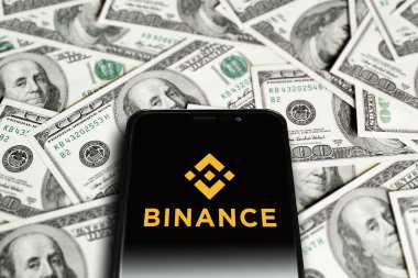 Smartphone with Binance logo on background of dollars. Binance is a cryptocurrency exchange. Moscow, Russia - November 1, 2022.