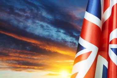 National flags of United Kingdom on a flagpole on sunset sky background. Lowered UK flags. Background with place for your text.