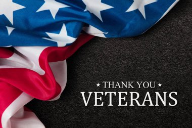Closeup of American flag with Text Thank You Veterans on black textured background. American holiday banner.