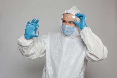 Closeup of vial to vaccinate in scientific virologist hand for immunization. Scientific virologist. Biologist in protective suit and blue gloves. Vaccination concept.