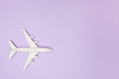 Uçak modeli. Mor arka planda beyaz bir uçak. Seyahat tatili konsepti. Yaz dönemi. Düz konum, üst görünüm, kopyalama alanı.