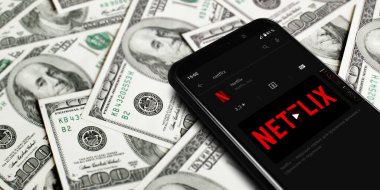Netflix logo on smartphone screen. Netflix streaming service for watching videos. Smartphone on background of dollars. Moscow, Russia - April 21, 2022.