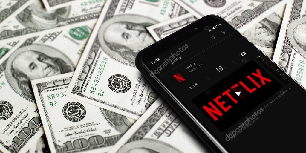 Netflix logo on smartphone screen. Netflix streaming service for watching videos. Smartphone on background of dollars. Moscow, Russia - April 21, 2022.