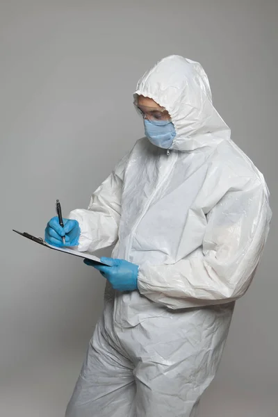 Scientific virologist. Biologist in protective suit and blue gloves takes notes. Viruses concept. Virus University employee.