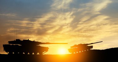 Silhouettes of army tanks at sunset sky background. Military machinery.