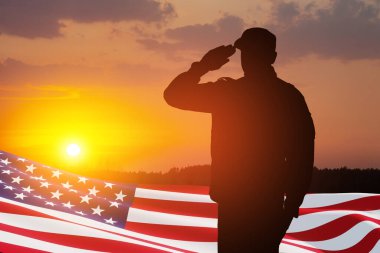 USA army soldier saluting with nation flag on a background of sunset or sunrise. Greeting card for Veterans Day, Memorial Day, Independence Day. America celebration.