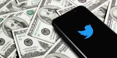 Blue Twitter logo on smartphone screen on background of dollars. Twitter is a microblogging and social networking service. Elon Musk closes Twitter acquisition deal. Moscow, Russia - October 27, 2022.