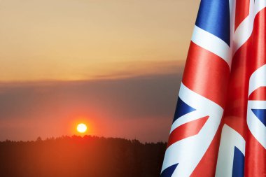 National flags of United Kingdom on a flagpole on sunset sky background. Lowered UK flags. Background with place for your text.